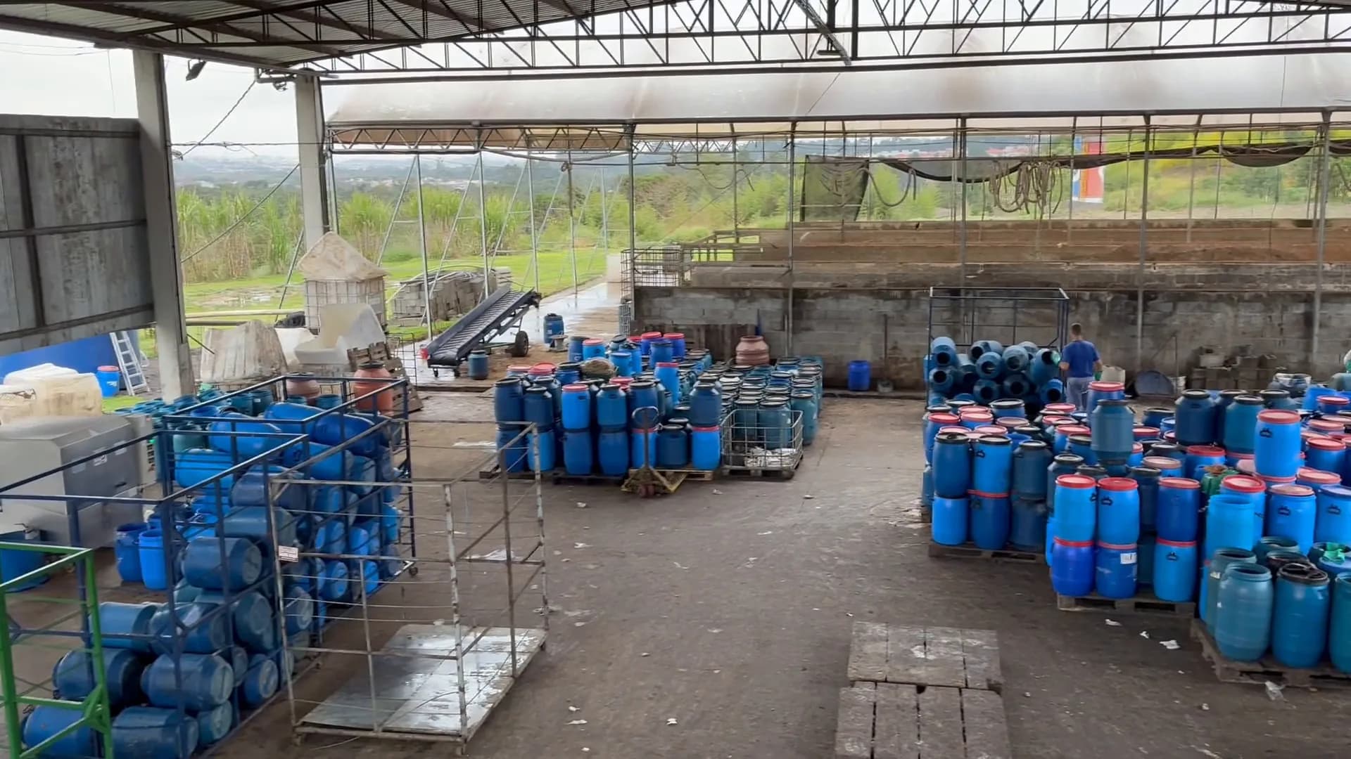 Overhead view of a covered area with blue collection drums, steel structures and equipment.