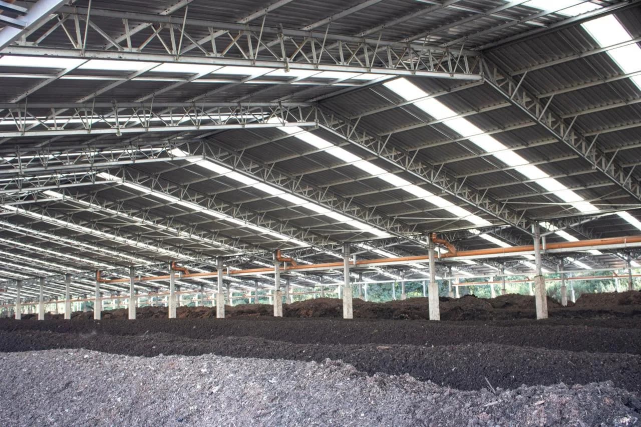 Composting windrows beneath the steel roof of a large facility.
